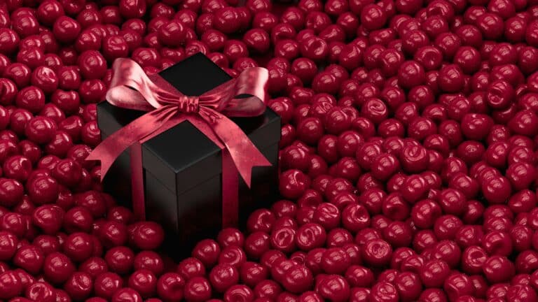 Black gift box with red ribbon surrounded by shiny red balls.